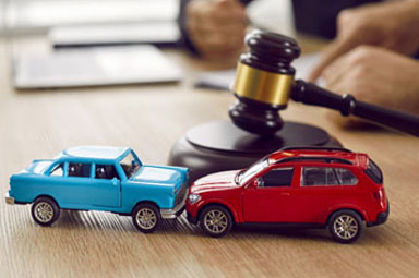 Two toy cars in collision with gavel on desk, symbolizing motor vehicle accidents in Georgia.