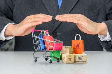 Person in suit shielding shopping cart, symbolizing product liability in online purchases.
