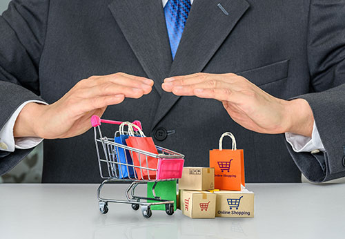 Hands hovering over a shopping cart with boxes, symbolizing consumer protection.