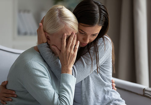 Woman comforting an elderly, distressed woman; potentially emotional support.